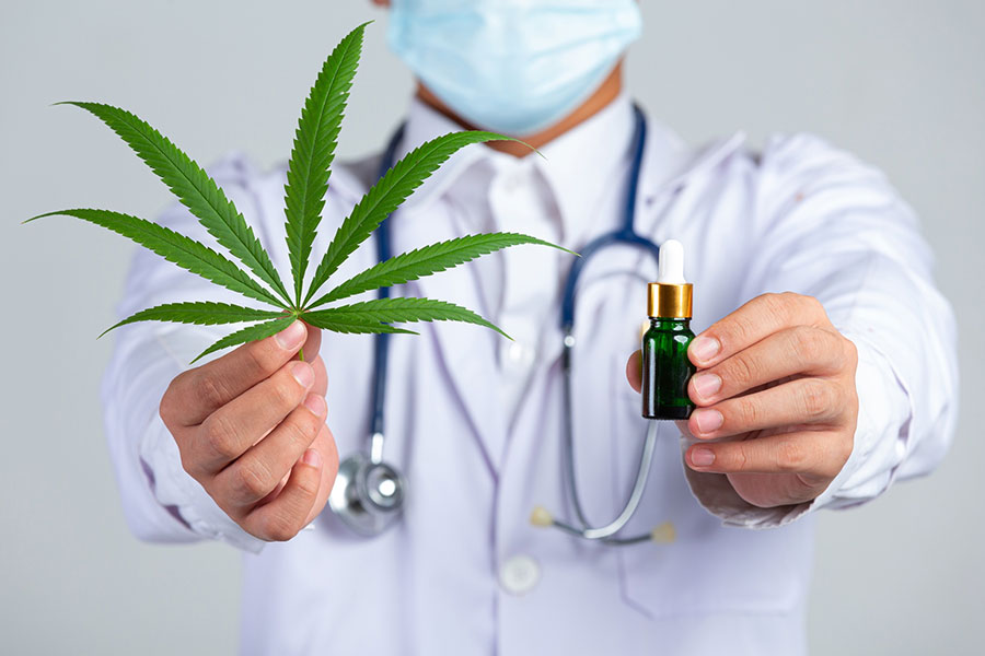 medical-doctor-holding-cannabis-leaf-bottle-cannabis-oil-white-wall-2
